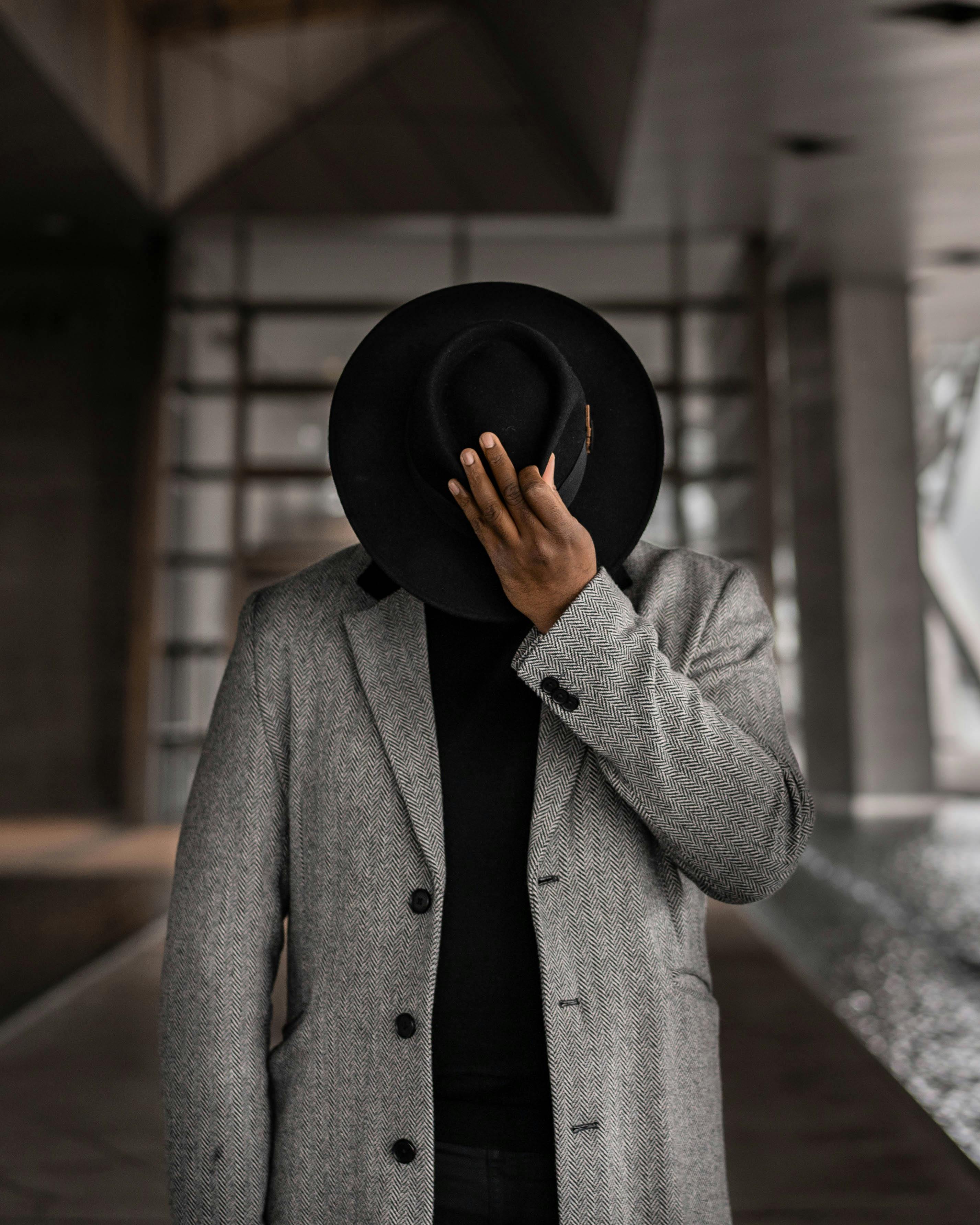 Man on black hat harsh colored suit with black buttons